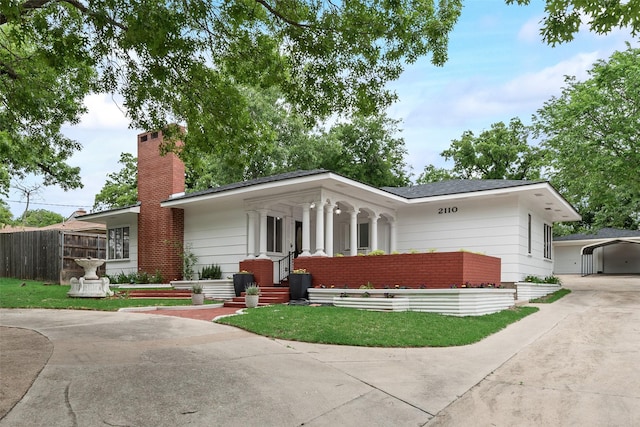 view of front of home featuring fence, covered porch, a chimney, concrete driveway, and a carport