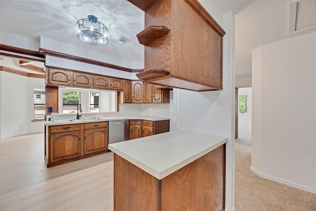 kitchen with a sink, dishwasher, brown cabinetry, a peninsula, and visible vents