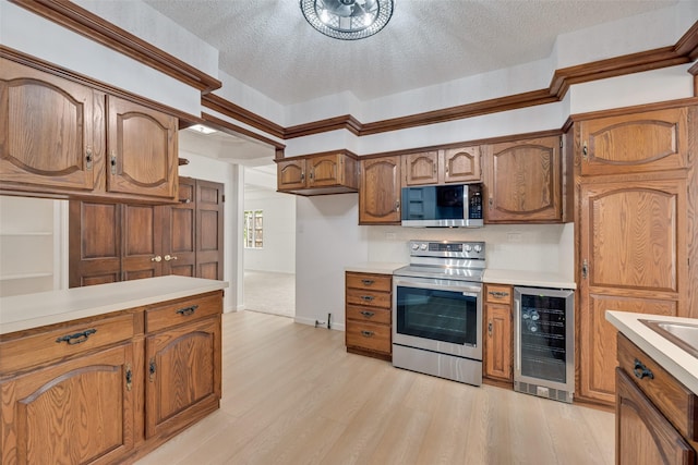 kitchen featuring light countertops, stainless steel appliances, brown cabinetry, and beverage cooler