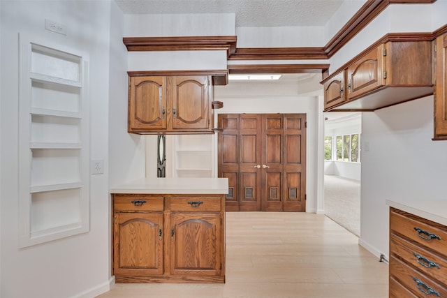 interior space with light countertops, baseboards, brown cabinetry, and light wood finished floors