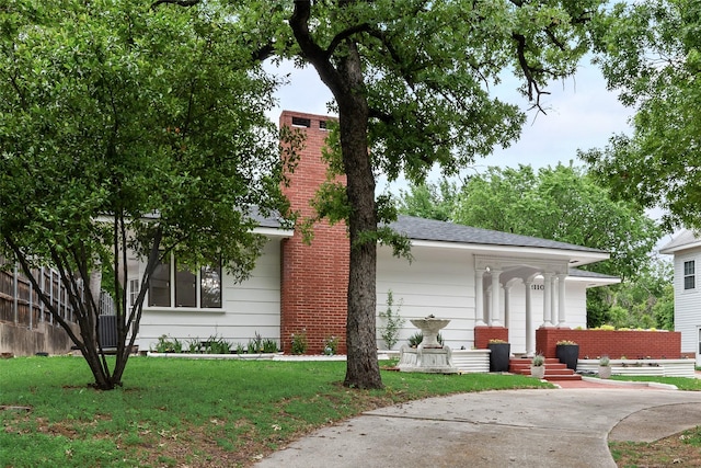 ranch-style home with a chimney and a front lawn