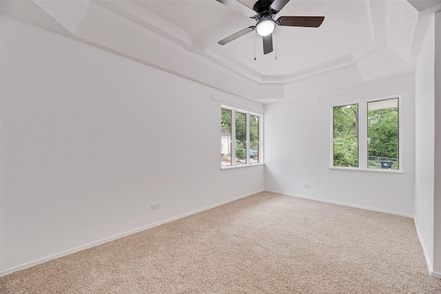 carpeted empty room with a raised ceiling, baseboards, and a ceiling fan