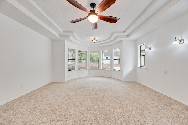 unfurnished room featuring light colored carpet, a raised ceiling, ceiling fan, and baseboards