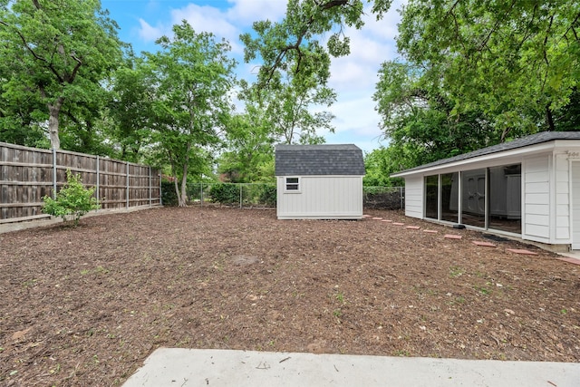 view of yard featuring an outdoor structure, a fenced backyard, and a storage shed