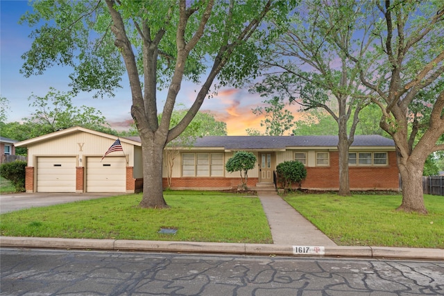 single story home featuring brick siding, a garage, a yard, and driveway