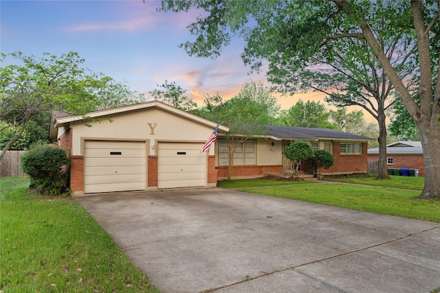ranch-style home featuring a lawn, brick siding, driveway, and a garage