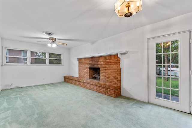 unfurnished living room with carpet floors, ceiling fan, a fireplace, and visible vents