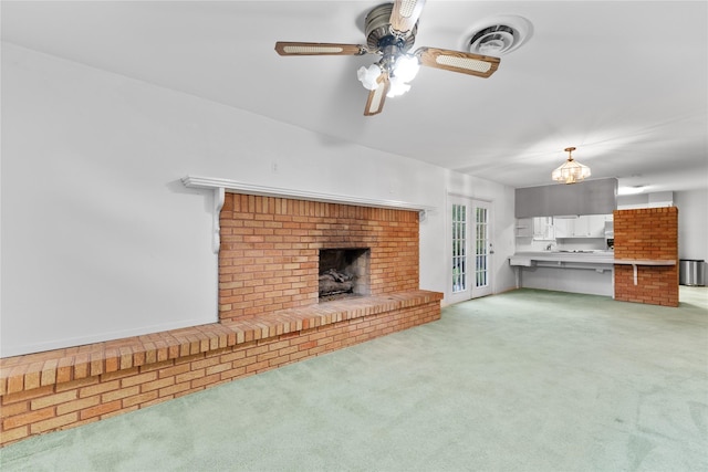 unfurnished living room featuring visible vents, a ceiling fan, a fireplace, and light colored carpet