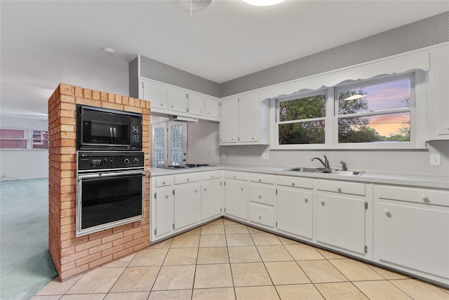 kitchen with light countertops, white cabinets, a sink, and black appliances