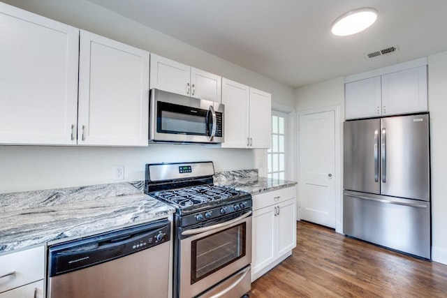 kitchen featuring white cabinets, light stone countertops, stainless steel appliances, and visible vents
