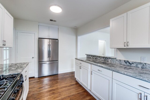 kitchen with stainless steel fridge, white cabinetry, and visible vents