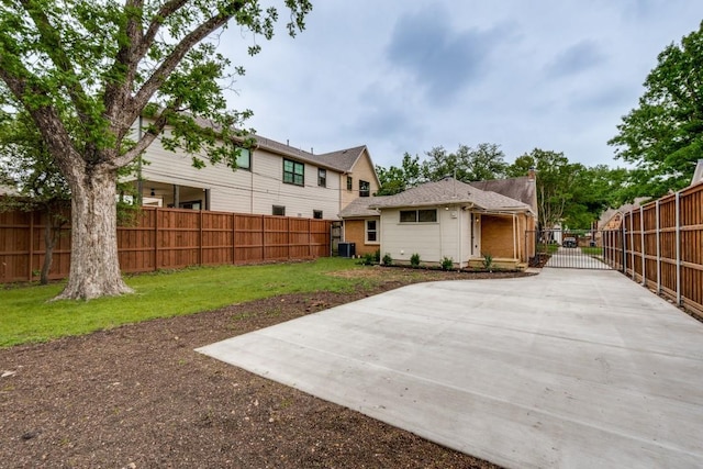back of house featuring fence, a gate, a lawn, and central AC