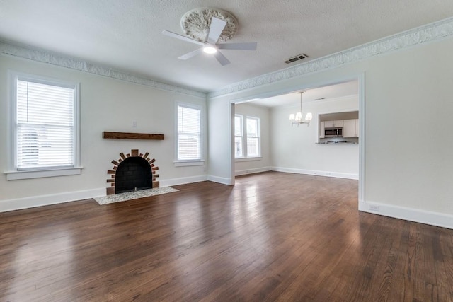 unfurnished living room featuring visible vents, a fireplace with flush hearth, wood finished floors, baseboards, and ceiling fan with notable chandelier