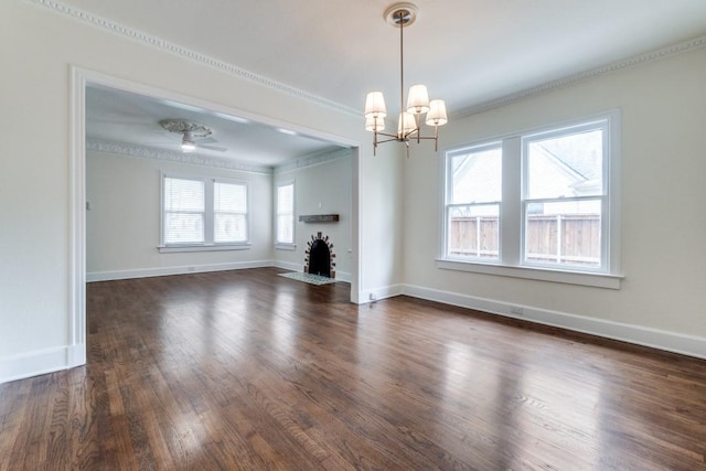 unfurnished dining area with an inviting chandelier, ornamental molding, baseboards, a fireplace with flush hearth, and dark wood-style floors