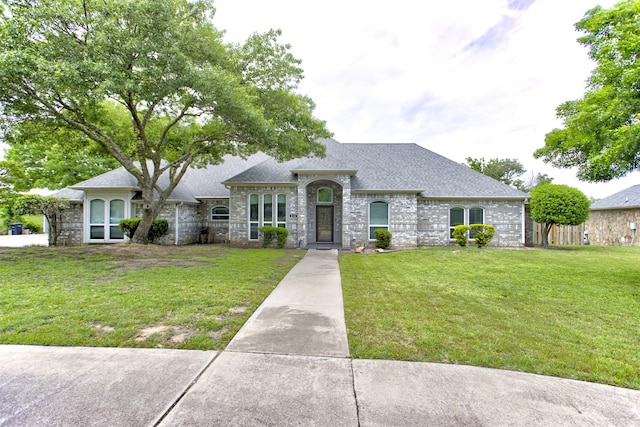 view of front facade featuring roof with shingles, stone siding, and a front yard