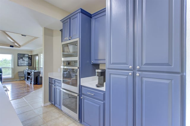 kitchen featuring blue cabinets, light countertops, open floor plan, stainless steel appliances, and light tile patterned flooring