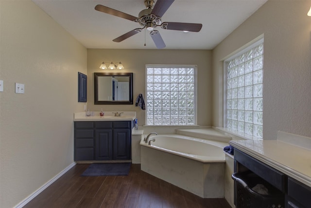 full bath with vanity, a garden tub, wood finished floors, baseboards, and ceiling fan