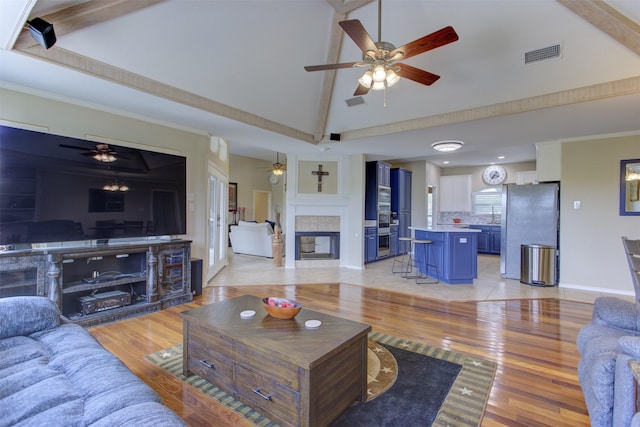 living area featuring visible vents, a multi sided fireplace, ceiling fan, and high vaulted ceiling