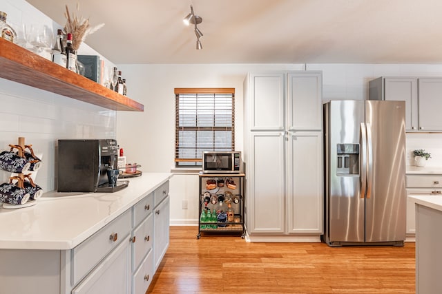 kitchen featuring open shelves, light wood finished floors, light countertops, stainless steel appliances, and gray cabinetry