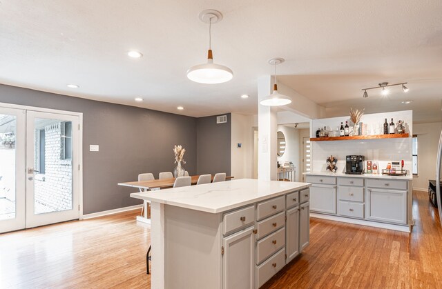 kitchen featuring light wood-style floors, a kitchen breakfast bar, french doors, gray cabinets, and a center island