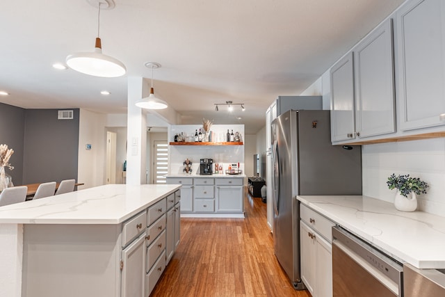 kitchen featuring gray cabinets, visible vents, appliances with stainless steel finishes, a center island, and light wood-type flooring
