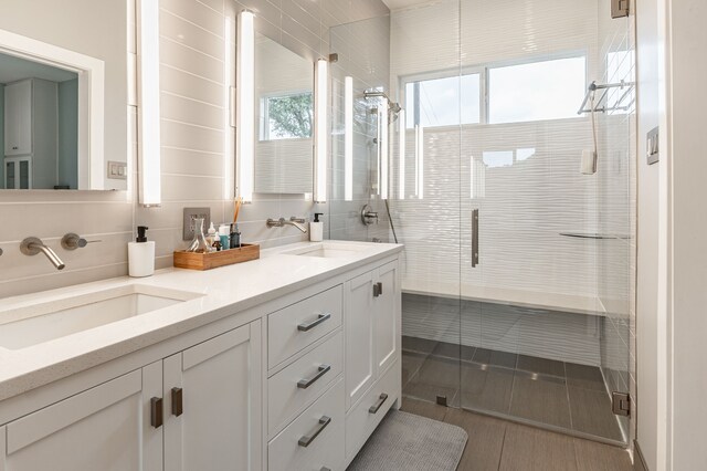 bathroom featuring a sink, a shower stall, and double vanity