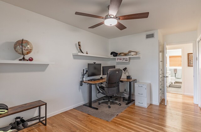 office space featuring ceiling fan, visible vents, baseboards, and light wood finished floors