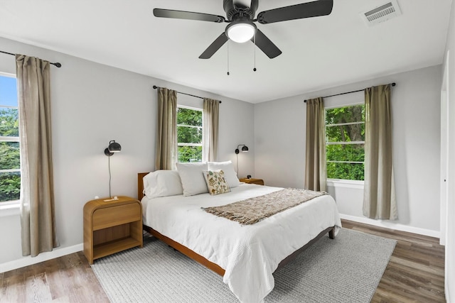bedroom with visible vents, a ceiling fan, baseboards, and wood finished floors