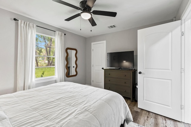 bedroom with a ceiling fan, wood finished floors, and visible vents