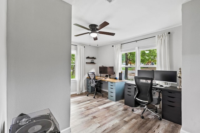 office area featuring baseboards, light wood-style flooring, ceiling fan, and a healthy amount of sunlight