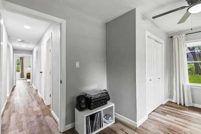 corridor with baseboards, attic access, and wood finished floors