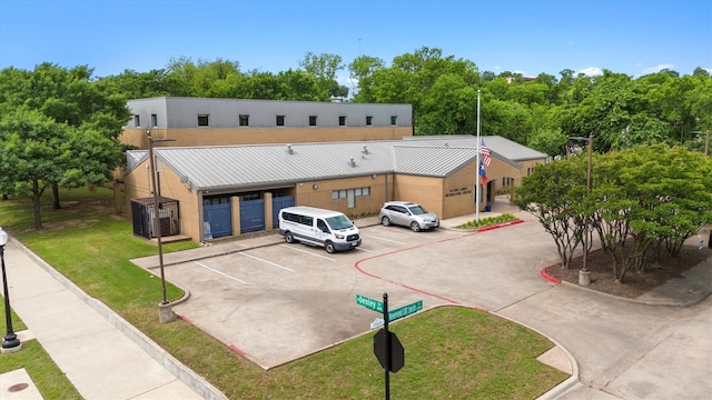 view of front facade featuring uncovered parking, metal roof, and a front yard