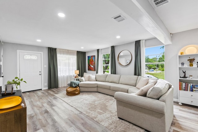living room featuring visible vents, a healthy amount of sunlight, and light wood-type flooring