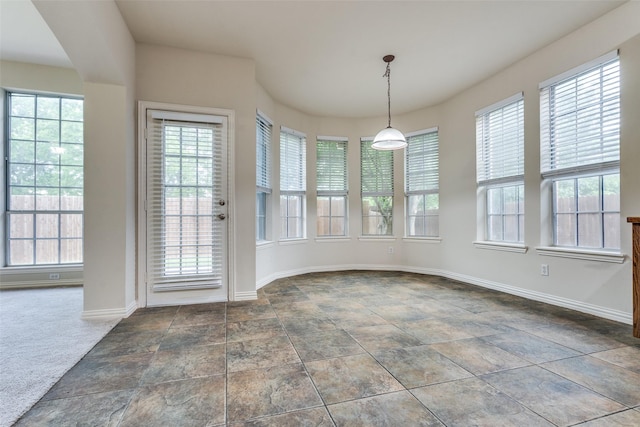 unfurnished dining area featuring baseboards, plenty of natural light, and stone finish flooring