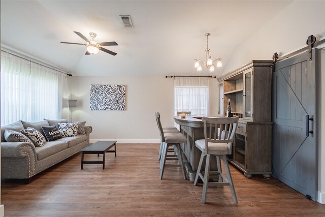 dining room with plenty of natural light, vaulted ceiling, a barn door, and visible vents
