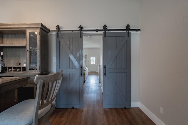 corridor with a barn door, baseboards, and wood finished floors