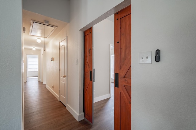 hall with baseboards, wood finished floors, and attic access