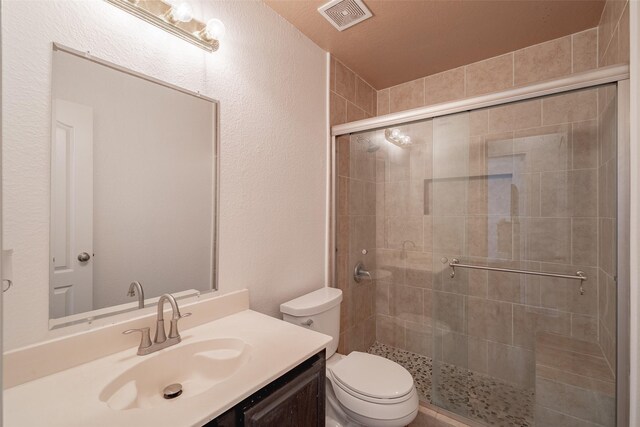 full bathroom featuring vanity, a stall shower, toilet, and visible vents