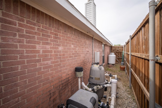 view of property exterior featuring fence, a chimney, and brick siding