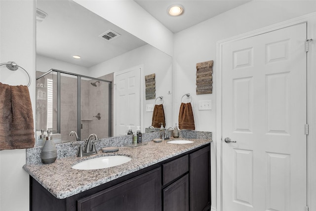 bathroom with double vanity, visible vents, a shower stall, and a sink