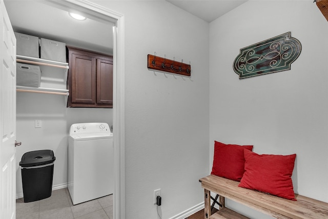 washroom with cabinet space, baseboards, washer / dryer, and light tile patterned floors
