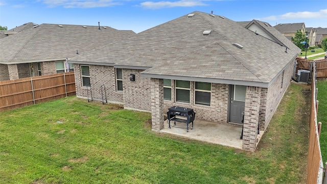 back of property featuring a lawn, central AC unit, brick siding, fence, and a patio
