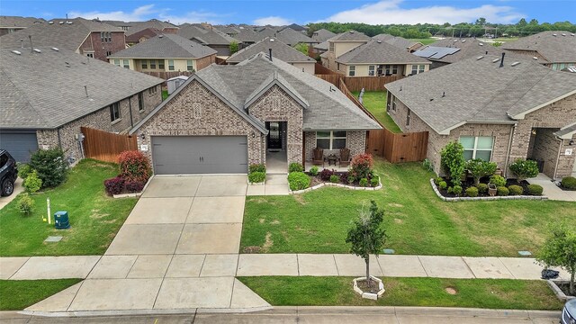 view of front of home with a garage, fence, brick siding, concrete driveway, and a residential view
