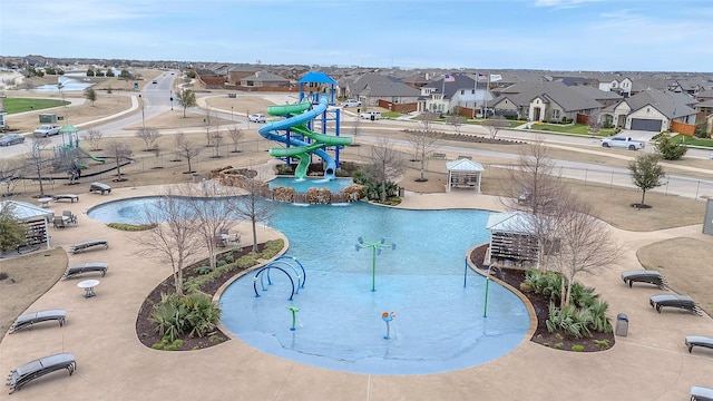 community pool featuring a residential view, a water slide, a water play area, and playground community