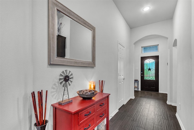 foyer entrance with dark wood-style flooring, arched walkways, baseboards, and recessed lighting