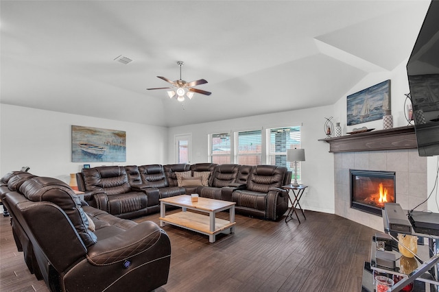 living area with ceiling fan, dark wood finished floors, lofted ceiling, a tile fireplace, and visible vents