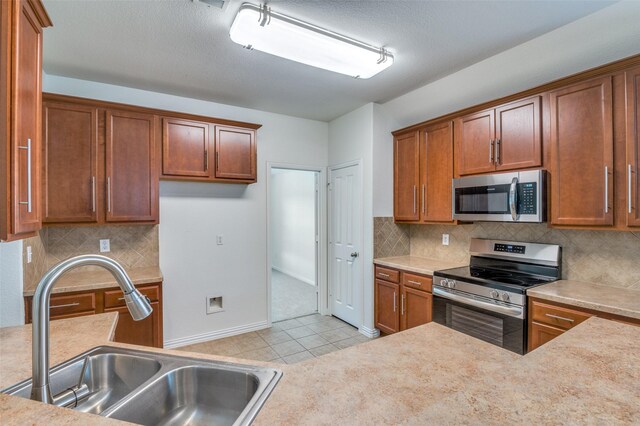 kitchen with a sink, light countertops, stainless steel appliances, and brown cabinets