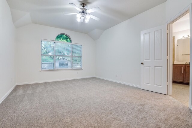 empty room featuring a ceiling fan, baseboards, light colored carpet, and lofted ceiling