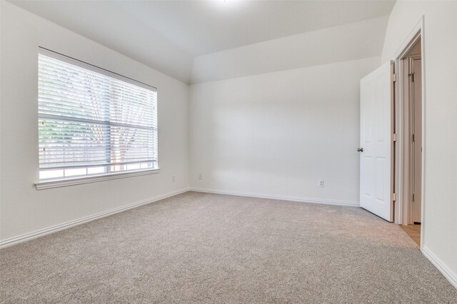 unfurnished room featuring baseboards, light carpet, and lofted ceiling