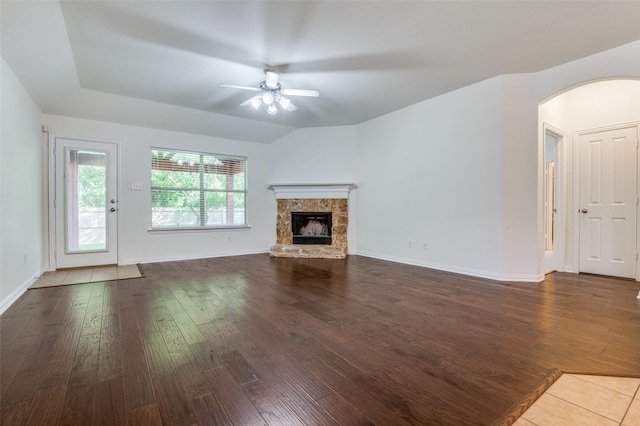 unfurnished living room featuring arched walkways, a ceiling fan, and dark wood-type flooring